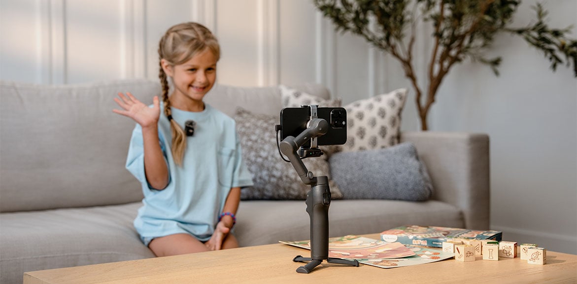 Dziewczynka używa gestów ręcznych nagrywając film na gimbalu DJI Osmo Mobile 8